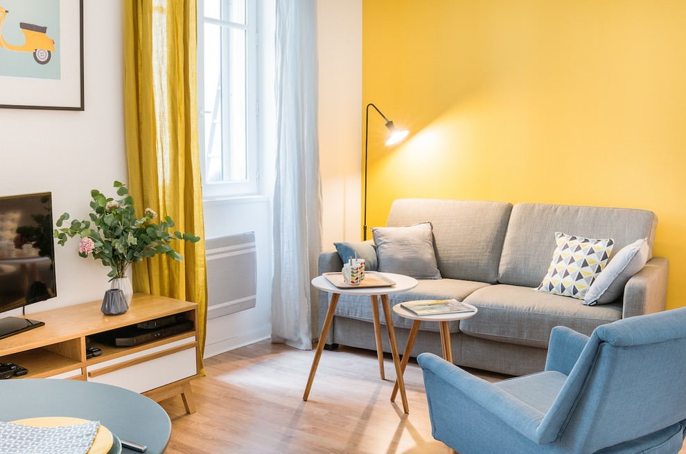 Серый диван на фоне желтой стены гостиной