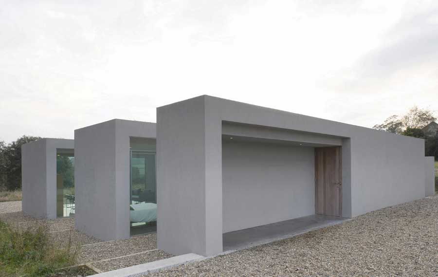 На фото фасад дома в стиле минимализм, пример отделки декоративной штукатуркой с имитацией бетона